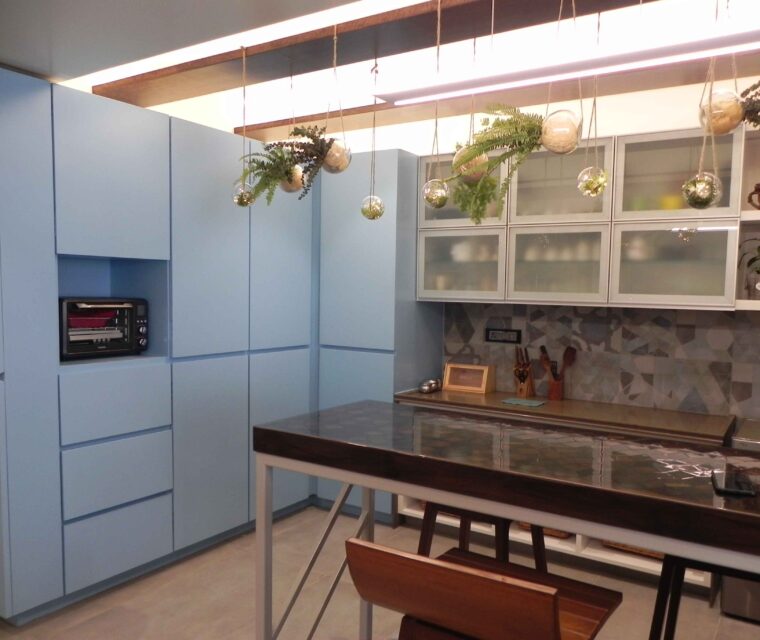 Modern kitchen interior with blue cabinets, island table, and hanging plants