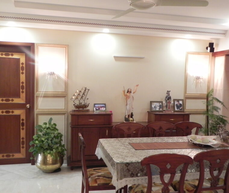 Cozy living room space with wooden sofas, cushions, and glass center table