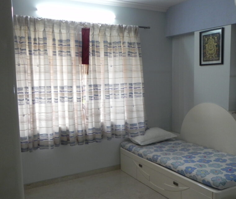 Minimalist bedroom with white wardrobe, wooden chair, and decorative mirror
