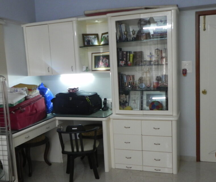 Functional home office corner with white cabinets and glass display shelves