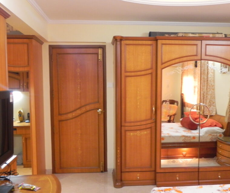Elegant wooden bedroom wardrobe with carved design and built-in mirror