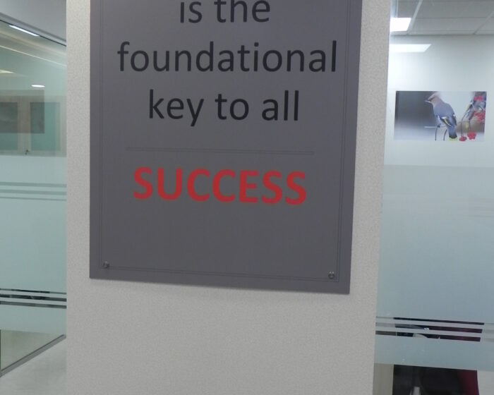 Motivational office signage with success quote on white wall for employee inspiration