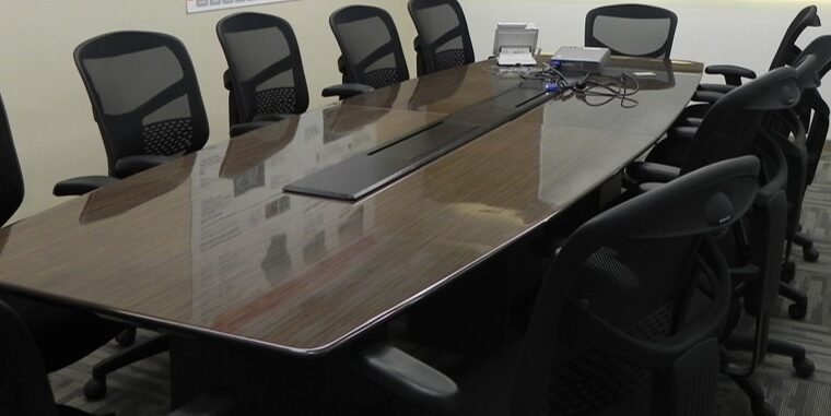 Spacious conference room with large meeting table and mesh executive chairs for corporate boardroom settings