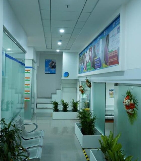 Contemporary hospital hallway with glass cabin doors, green plants, and informational wall posters – healthcare facility corridor interior