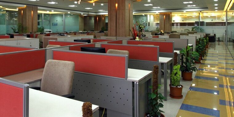 Spacious open-plan office space with modular workstations, ergonomic chairs, and glass partition walls – corporate workspace interiors