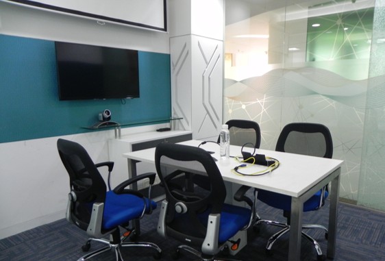 Modern office meeting room with four chairs, conference table, and wall-mounted TV setup